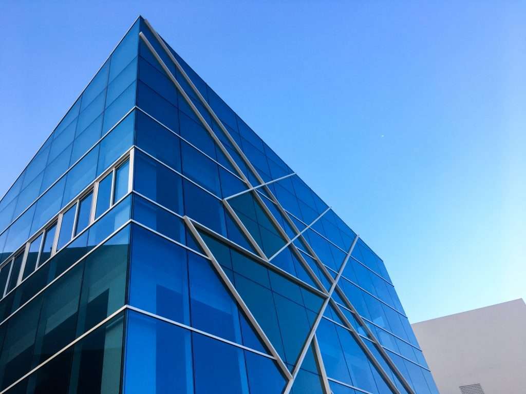 Moderne Glasfassade mit blauer Verspiegelung und diagonalen Tragprofilen – Fassadenbau in zeitgenössischer Architektur.