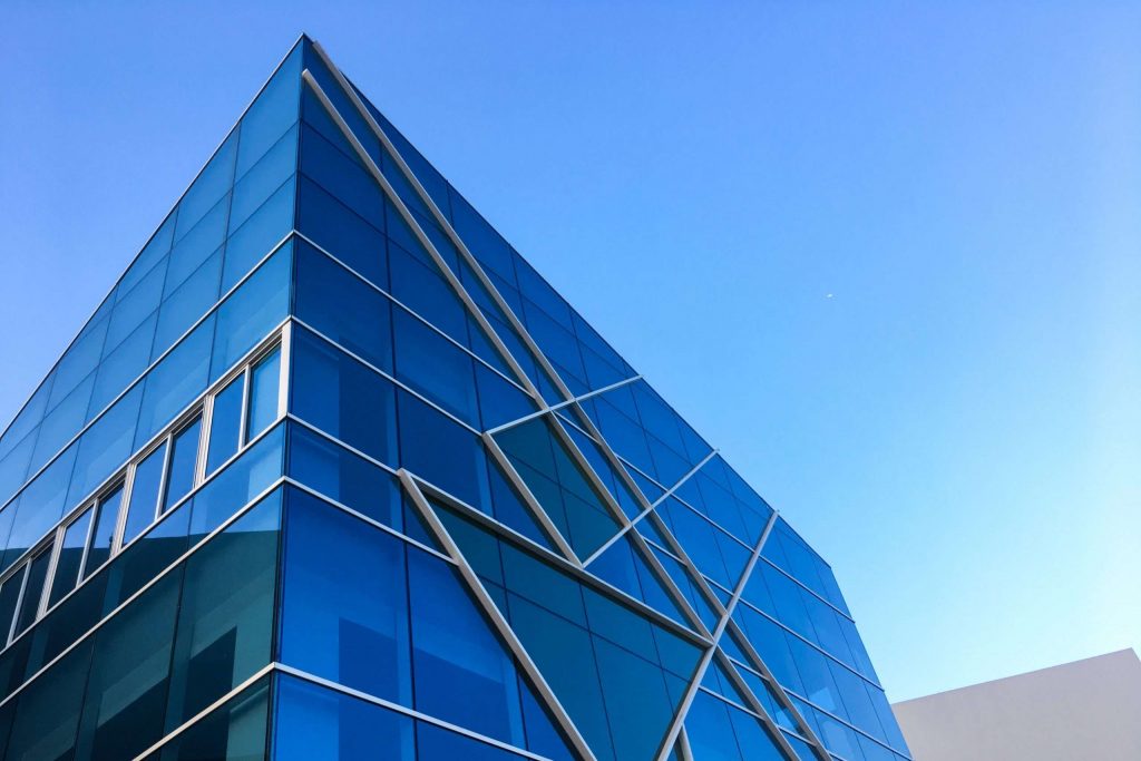 Moderne Glasfassade mit blauer Verspiegelung und diagonalen Tragprofilen – Fassadenbau in zeitgenössischer Architektur.
