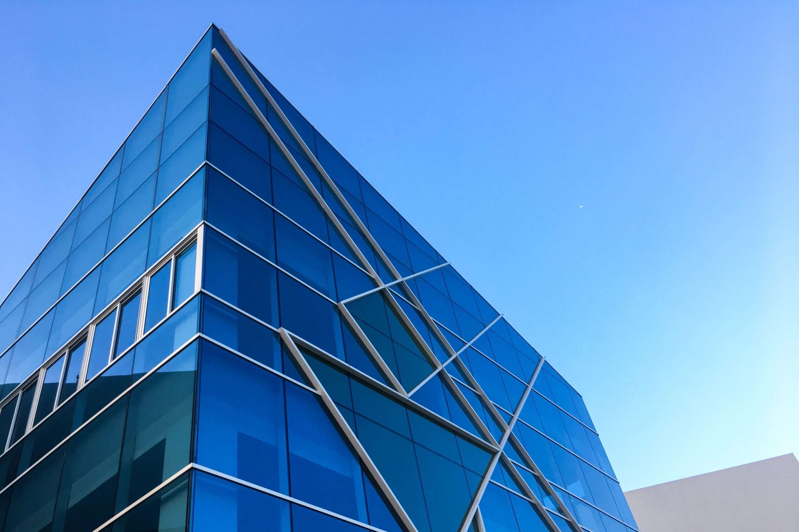 Moderne Glasfassade mit blauer Verspiegelung und diagonalen Tragprofilen – Fassadenbau in zeitgenössischer Architektur.
