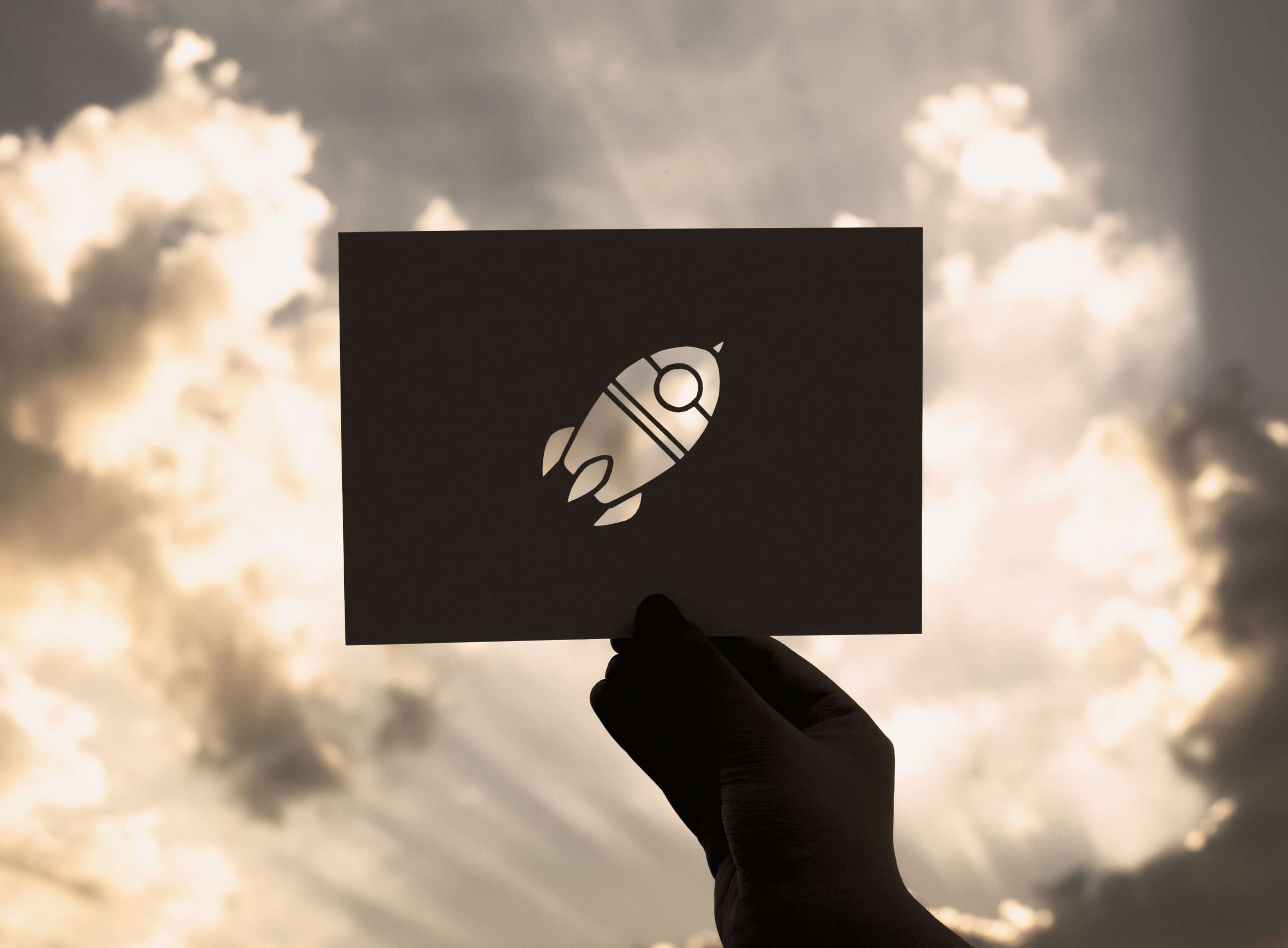 Eine Hand hält eine Karte mit ausgestanztem Raketensymbol gegen den Himmel – sinnbildlich für Aufbruch, Innovation und den digitalen Fortschritt von vision4project.